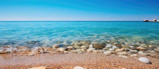 Poster - Copy space image showcasing rocks and sand in the ocean under a clear blue sky with a water backdrop.
