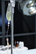 © Seventyfour - Vertical closeup of IV drip stand with fluids by operating theater in hospital copy space
