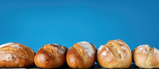 Fototapete - Three freshly baked loaves of bread are arranged in the corner against a blue backdrop, leaving space for your text. with copy space image. Place for adding text or design