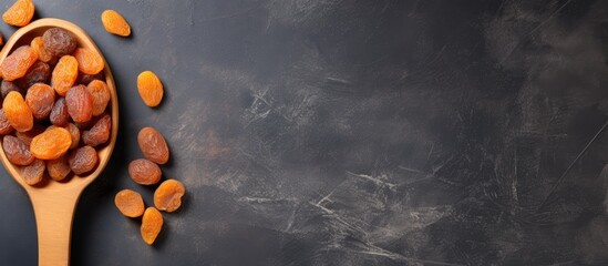 Wall Mural - Wooden spoon filled with delicious dried apricots on a grey backdrop with copy space image.