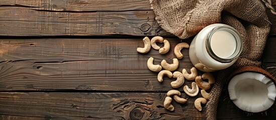 Aufkleber - Top view of a glass bottle with coconut milk and cashew nuts on a brown wooden surface, featuring copy space image.