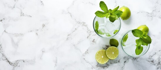 Poster - Top view of two highball glasses with a traditional Mojito cocktail served in a bar. The drink features rum, spearmint, lime juice, soda water, and ice, placed on a white concrete table with ample