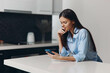 © SHOTPRIME STUDIO - Woman using smartphone at table in modern kitchen, checking messages and notifications while relaxing at home