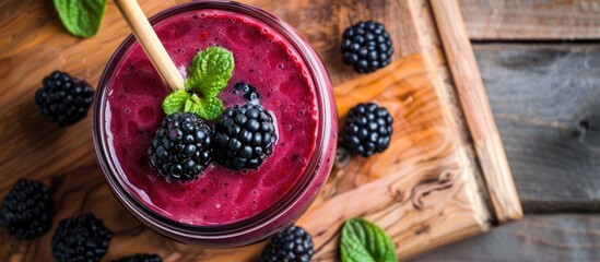 Poster - A fresh blackberry smoothie in a glass jar with a bamboo straw on a wooden background, viewed from the top with close-up details, providing copy space for an image, exemplifying a healthy food