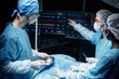 © Seventyfour - Side view portrait of surgical team performing operation in blue lights and looking at monitors with heart rate