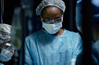 © Seventyfour - Waist up portrait of young African American female surgeon performing surgery in operating room in dramatic blue light