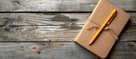 Leinwandbilder - A brown notebook and pencil placed on a wooden desk, creating a serene copy space image.