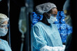 © Seventyfour - Side view portrait of African American woman as female surgeon wearing full protective clothing in operation with screens and monitors in background copy space