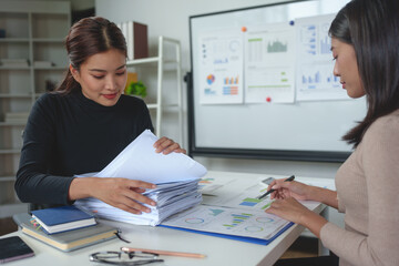 Wall Mural - Confident businesswoman working with laptop in office Female office worker uses a calculator to perform financial calculations. Search for piles of documents, accounting, online marketing.