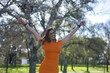 © Manuel - Young, beautiful woman in an orange dress, very happy and content, with open arms as a sign of gratitude. Concept beauty, fashion, fun, happiness, gratitude.