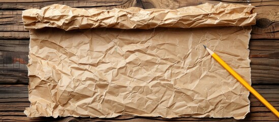 Poster - Wooden table with crumpled brown paper sheet and pencil, with free space for an image. copy space available