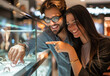 © Kien - A happy couple is shopping for jewelry at the mall, standing next to each other and pointing at an exquisite ring on display inside glass shelves