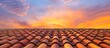 © Lasvu - Clay tile roof against a vibrant sunset sky with an orange banner, allowing room for text.