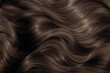 © Vera - Brown hair close-up as a background. Women's long brown hair. Beautifully styled wavy shiny curls. Hair coloring. Hairdressing procedures, extension.
