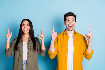 Wall Mural - Photo of two nice young partners look indicate fingers up empty space wear shirt isolated on blue color background