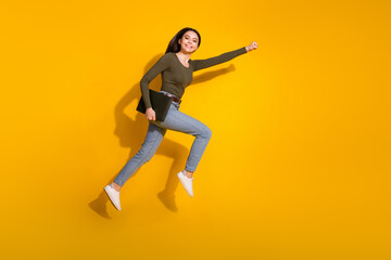 Canvas Print - Full body photo of attractive teen woman flying superman hold netbook dressed stylish khaki clothes isolated on yellow color background