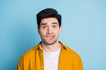 Poster - Photo of attractive uncertian guy wear yellow shirt biting lip emtpy space isolated blue color background