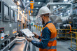 © Anna - Industrial worker using a digital tablet to monitor machinery in a modern factory.