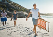 © Stratford/peopleimages.com - Walking, friends and happy at beach with chair for picnic, weekend and summer in nature. Men, social and sunshine at ocean or sea with sand and wellness for travel, adventure and holiday in Miami