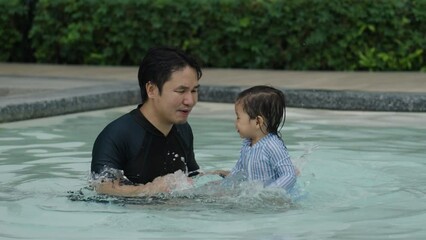 Wall Mural - happy father with todler baby playing water splashing in a swimming pool