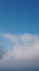 Wall Mural - drone flies over foggy and fluffy clouds. aerial vertical view. blue sky sun and sea fog. abstract a