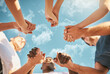 © Stratford/peopleimages.com - People, holding hands and below with blue sky for teamwork, motivation or solidarity in nature. Low angle of friends or diverse group touching on outdoor mission for inclusion, collaboration or unity