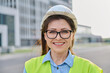 © Valerii Honcharuk - Headshot portrait of woman in safety helmet vest looking at camera outdoors