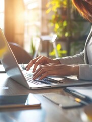 a woman is typing on a laptop in front of a potted plant