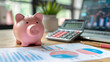 © SebuahKisah - Pink piggy bank on desk with charts, calculator, and laptop, symbolizing personal finance, savings, and investment.