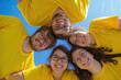 © vefimov - A group of people wearing yellow shirts are smiling and posing for a picture