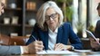 © Bundi - Several businessmen are seated at a desk under the direction of a serious-looking woman wearing glasses checking an agreement document before signing it. A financial director stands ready with his