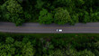 © Kalyakan - Aerial view electric vehicle car driving on asphalt road in mountain green forest, EV car electric vehicle car on forest road green energy and eco power, White electric car driving green forest road.