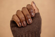 © Seventyfour - Close up shot of simple nail design in rich brown shade for autumn complementing outfit on beige background