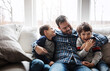 © Reese Coop/peopleimages.com - Happy, hug and father with children on sofa for bonding, loving relationship and relax together in home. Family, love and dad with young boys embrace for affection, care and smile in living room