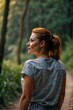 © sergio - A woman standing in a lush green forest, wearing a blue shirt and jeans, looking at the view. AI.