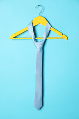Wall Mural - Hanger with silk tie on light blue background