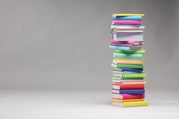 Wall Mural - Stack of colorful books on light grey background, space for text