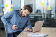 © Tetiana - Businessman experiencing stomach pain at office while working on laptop