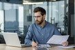 © Tetiana - Serious financier working on paperwork and analyzing data in modern office