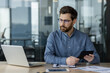 © Tetiana - Serious accountant working on financial analysis using laptop in modern office
