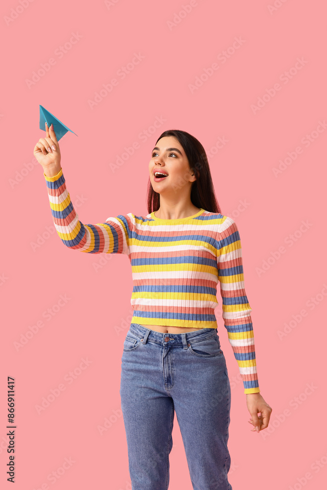 Happy young woman with paper plane on pink background