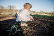© Maryna - Young Child Examining Sprouting Onion Plants in a Garden Bed