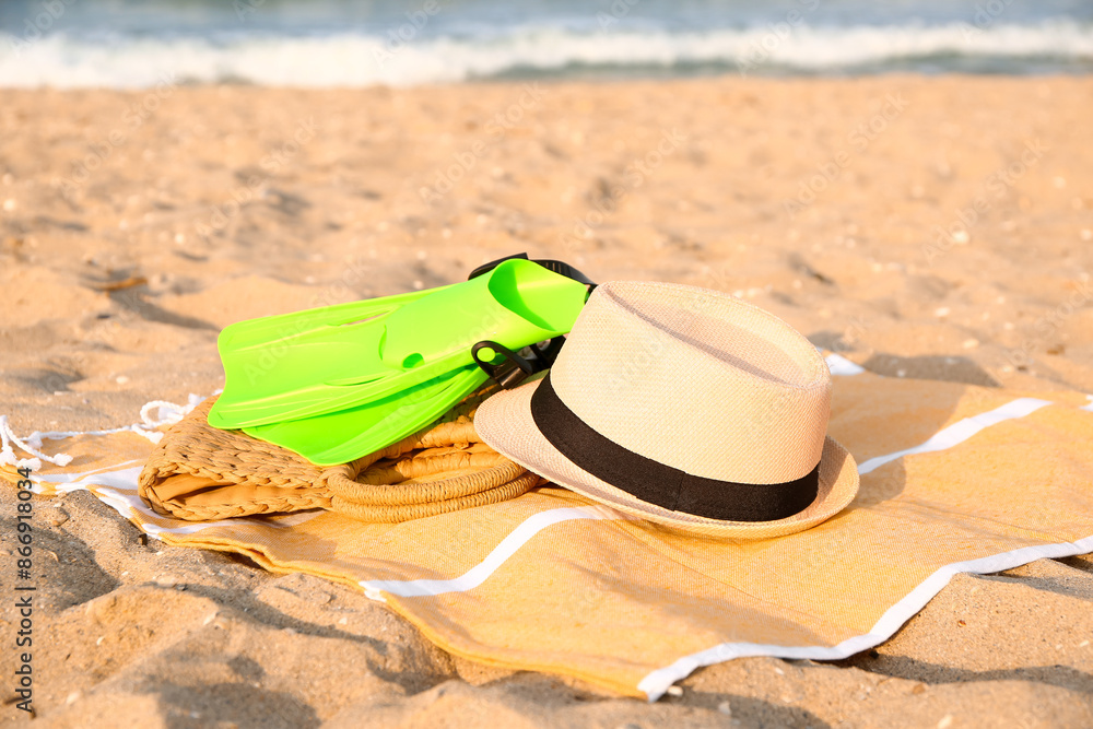 Towel with hat, bag and flippers on sand