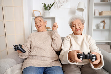 Wall Mural - Senior female friends playing video game on sofa at home