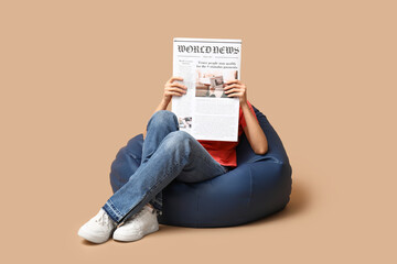 Canvas Print - Woman in beanbag chair with newspaper on beige background