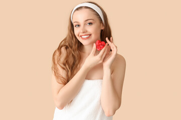 Wall Mural - Beautiful young woman with heart-shaped soap on beige background