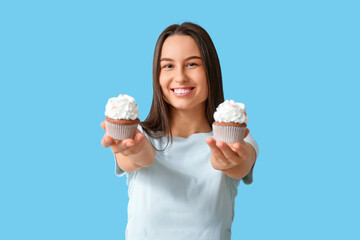 Wall Mural - Young woman with sweet cupcakes on blue background. Valentine's Day celebration