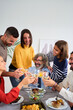 © CarlosBarquero - Vertical. Happy Caucasian people toasting with white wine at a meal at home. Smiling family of diverse generations together around the table at festive event at weekend. Domestic life celebration