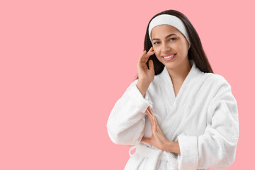 Wall Mural - Beautiful young happy woman in bathrobe on pink background