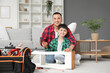 © Pixel-Shot - Cute little boy with his father repairing table at home